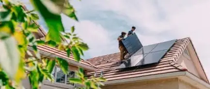 Zwei Monteure installieren eine Solaranlage auf einem Dach